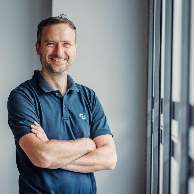 Man in een Carado-polo met zijn armen over elkaar bij het raam