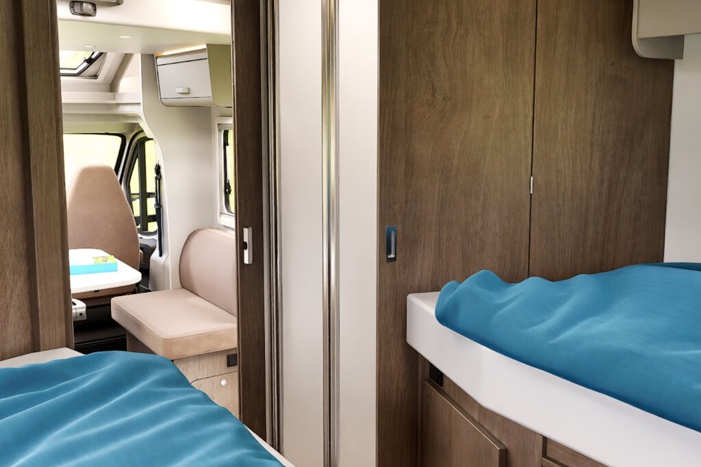 Schlafbereich im Carado Wohnmobil mit zwei Einzelbetten, Holzschränken und Blick zur Sitzgruppe