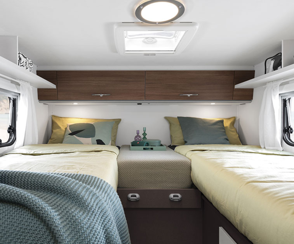 Interior of an Etrusco semi-integrated motorhome on a Ford base with cozy single beds and modern design.