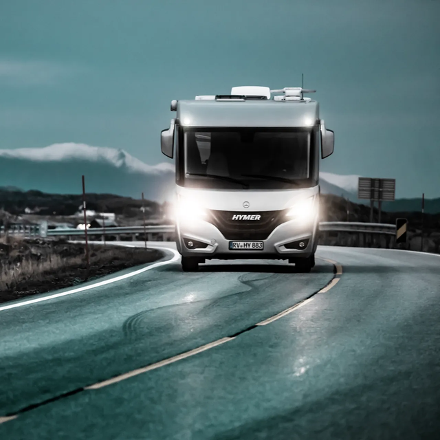 Beleuchtetes, fahrendes HYMER-Reisemobil B-ML I auf glatter Straße in Abenddämmerung auf atlantischer Straße 