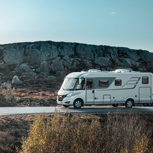 HYMER B-Klasse MasterLine von der Seite auf einer Straße in Skandinavien mit typischer Hügellandschaft am Straßenrand