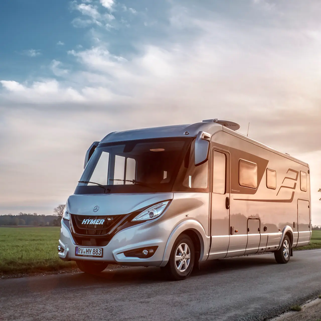 HYMER B-Klasse Masterline auf Straße in ebener Landschaft mit grünen Wiesen und Bäumen