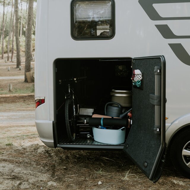 Mit Fahrrad, Gießkanne, Isomaten etc. beladene Heckgarage eines HYMER Reisemobils