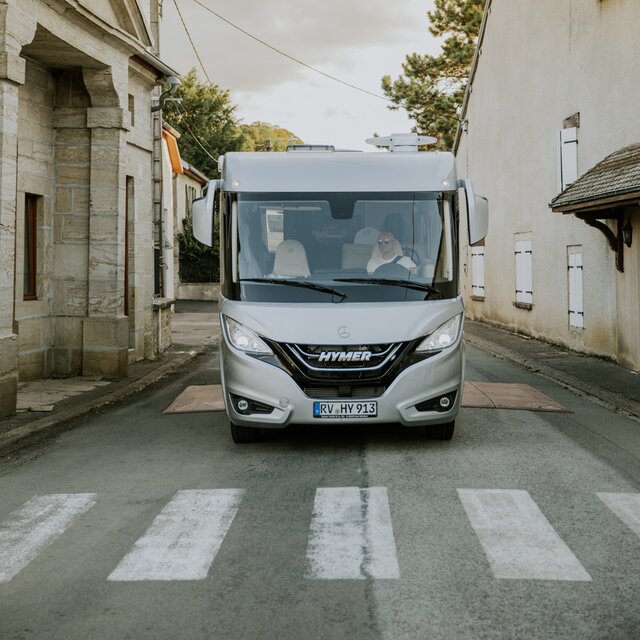 Frontansicht eines vollintegrierten HYMER Wohnmobils B-ML I vor Zebrastreifen in Ortschaft