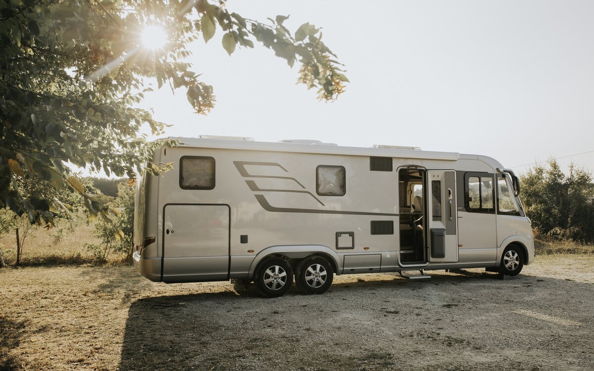 An Feldrand parkende HYMER B-Klasse MasterLine I mit geöffneter Aufbautüre als Doppelachser in warmer Lichtstimmung