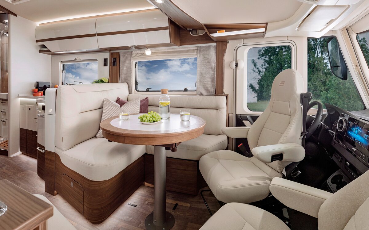 Wohnraum im HYMER-B-MasterLine mit Sitzmöglichkeit in cremefarbener Lederoptik am runden Tisch