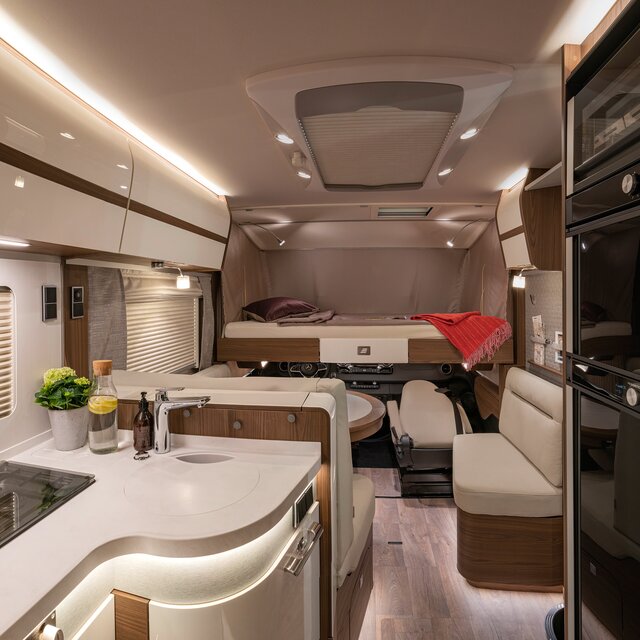 Absenkbares Bugbett mit roter Bettdecke und dunkelrotem Dekokissen in HYMER-B-Klasse MasterLine I 880