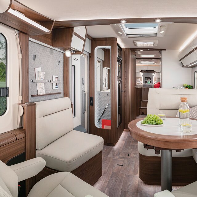 Wohnraum im HYMER-B-MasterLine mit Sitzgruppe in cremefarbener Lederoptik am gedeckten runden Tisch