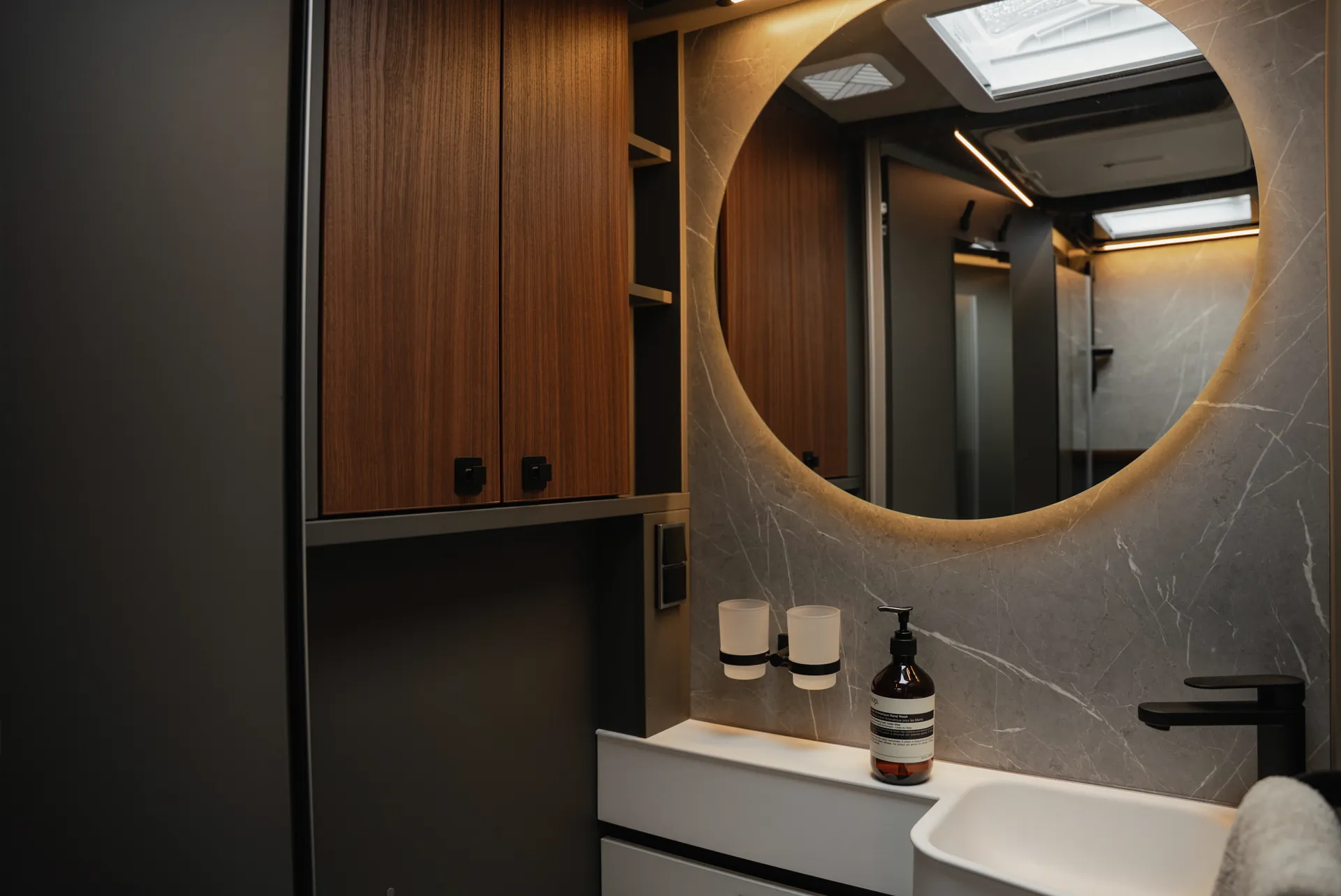 Der beleuchtete Rundspiegel und die indirekte Ambientebeleuchtung schaffen eine Atmosphäre, die Wertigkeit, Ruhe und modernes Design harmonisch vereint.