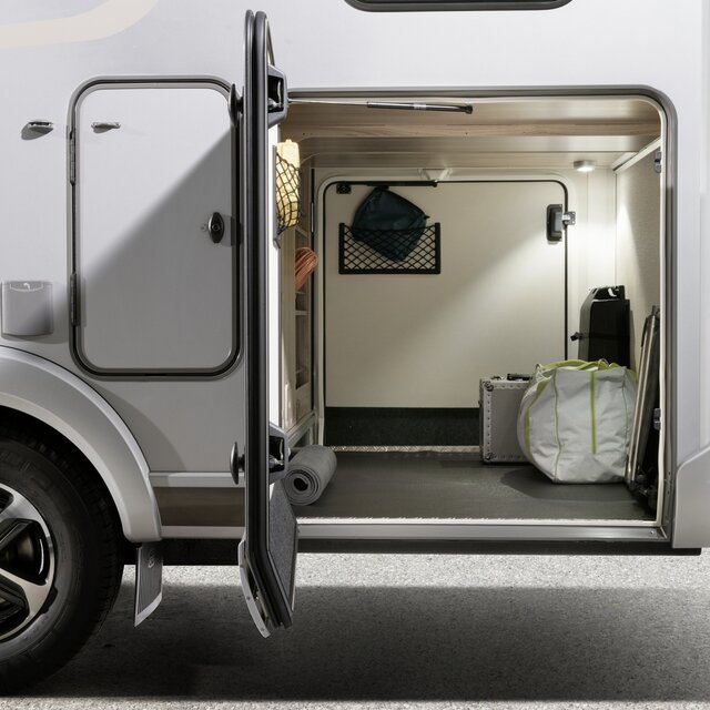 Geöffnete Garagentüre einer beleuchteten Wohnmobil-Heckgarage, die mit kleinerem Gepäck beladen ist