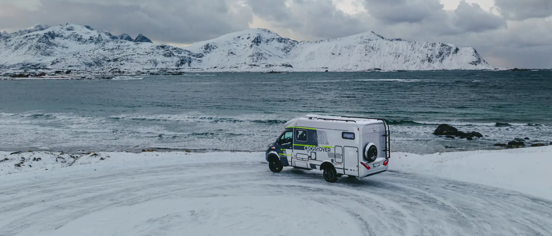HYMER ML-T 570 CrossOver parkert ved et utsiktspunkt, havet og snødekte fjell i bakgrunnen