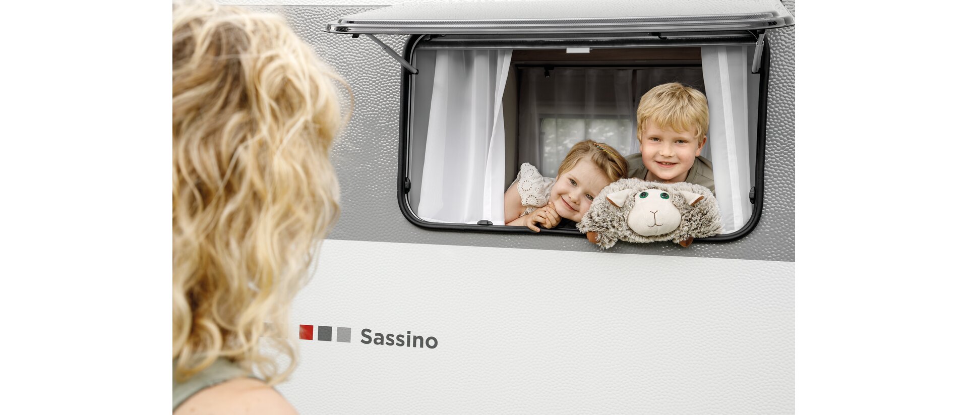 2 Kinder schauen aus einem geöffneten LMC Sassino Fenster raus